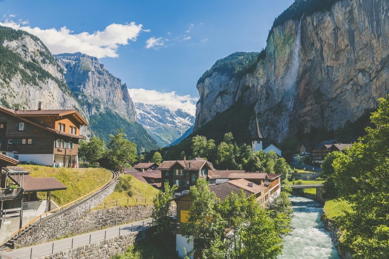 Lauterbrunnen with chalets, Staubbach Falls on the rock face and mountains in the background